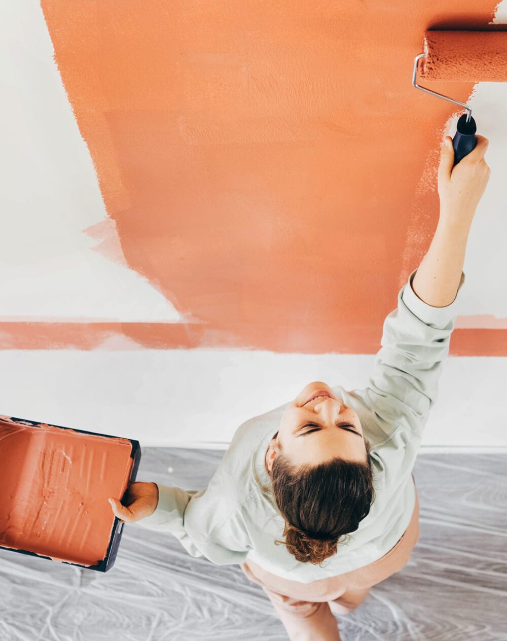 woman with paint roller painting wall 9NXC5S9